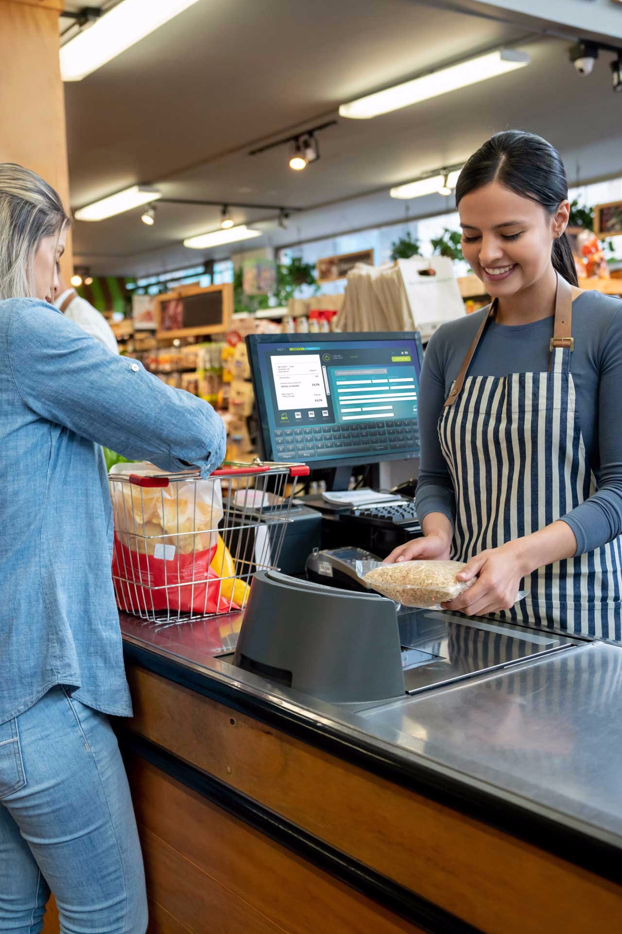 Cheerful employees at supermarket doing checkout for customers