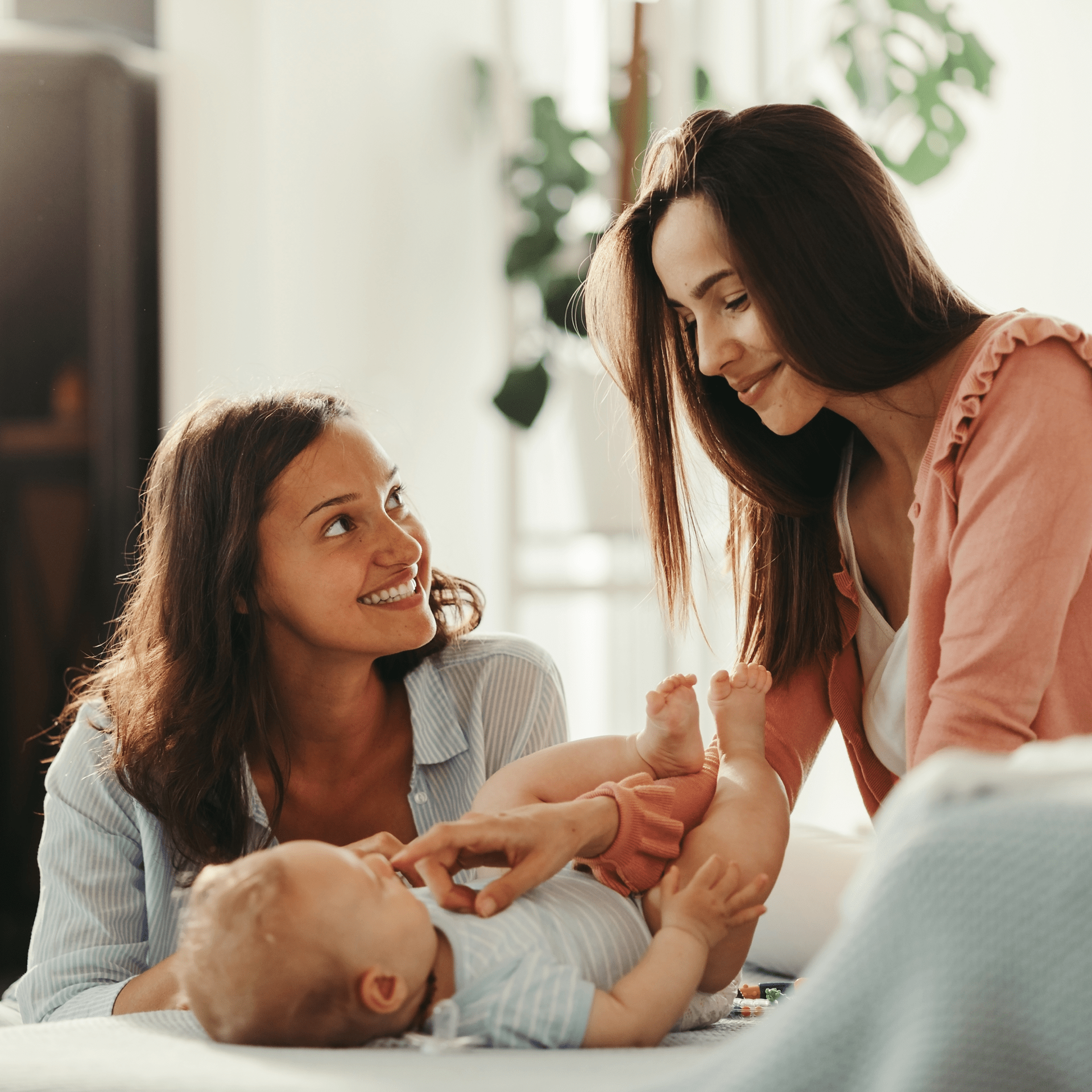 Two happy women having fun with their baby at home