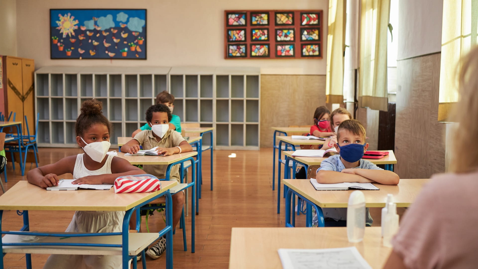 Group of elementary children studying with a teacher at school during coronavirus pandemic