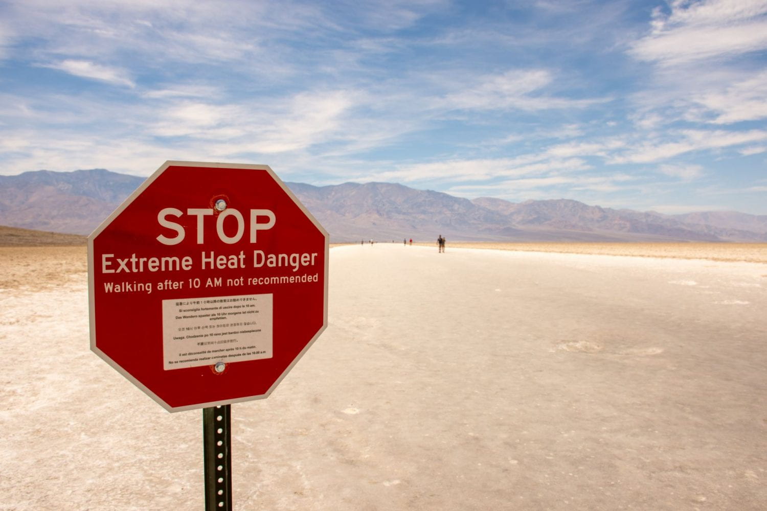 Stop Sign with extreme heat warning in the middle of a desert.