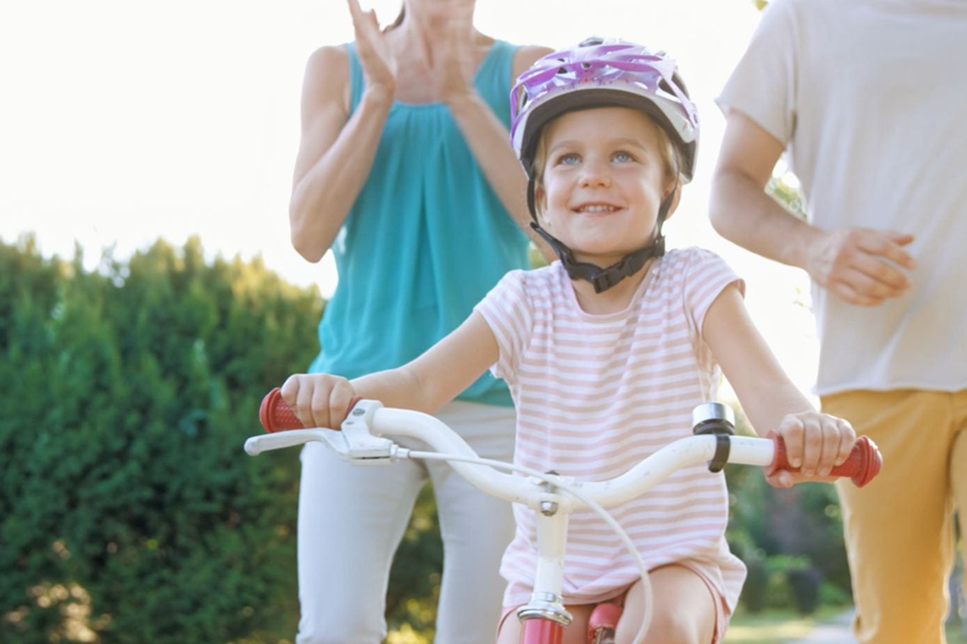 Girl riding her bike with parents helping